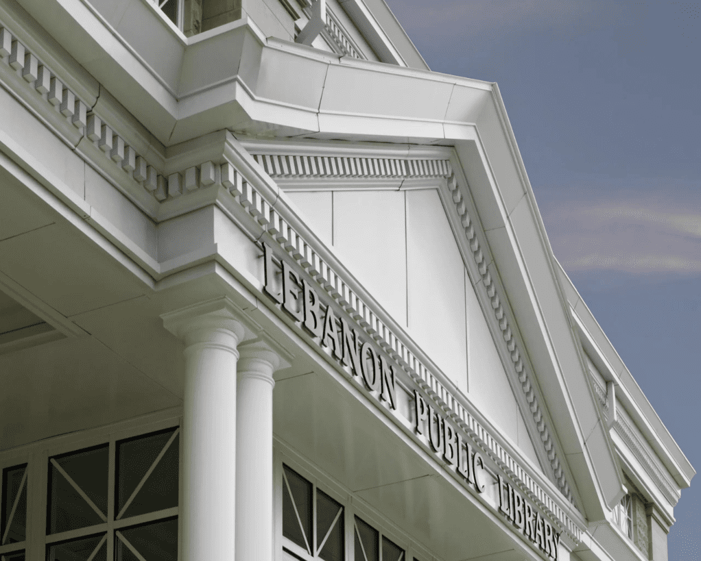 Untitled design (1) Exterior of the Lebanon Public Library building featuring classical architectural elements, including columns and detailed moldings, with a clear, blue sky background.